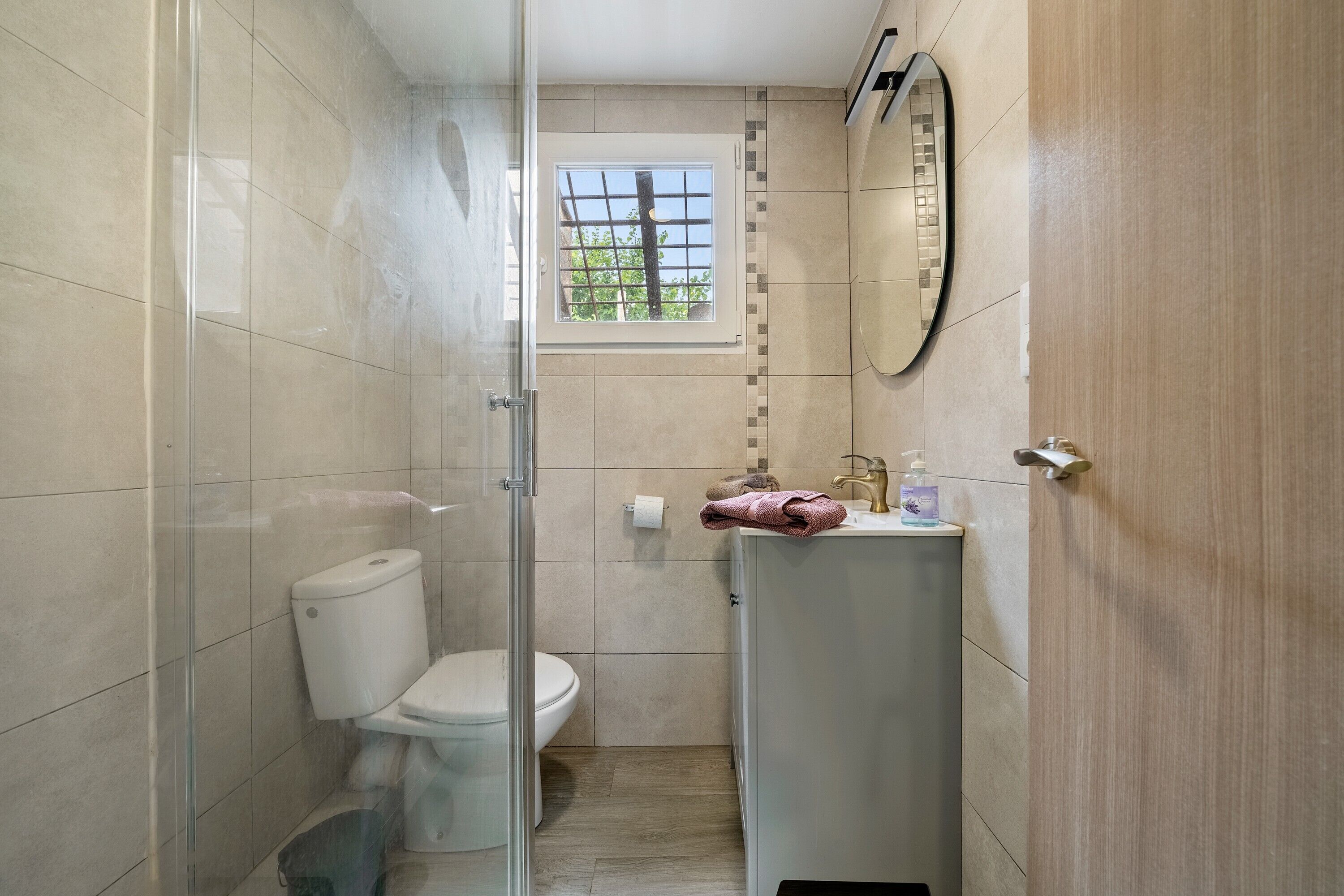 A bathroom with a toilet, a sink, a mirror, and a window.