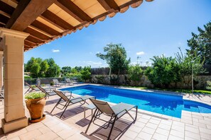 Una piscina con sillones de descanso y una pérgola.