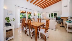 A spacious living area with a wooden dining table, white sofas, and a TV. - Villa 'Victoria' with Private Pool, Wi-Fi and Air Conditioning (Crestatx)