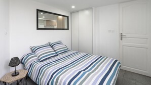 Ein Schlafzimmer mit einem Bett, einem Nachttisch mit Lampe, einem Spiegel und einem Kleiderschrank.