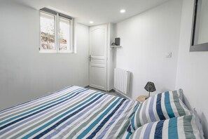 A bedroom with a bed, a window, a door, a radiator, and a lamp. - Holiday Apartment "Dans Maison Atypique" with Wi-Fi (Montrond-les-Bains)