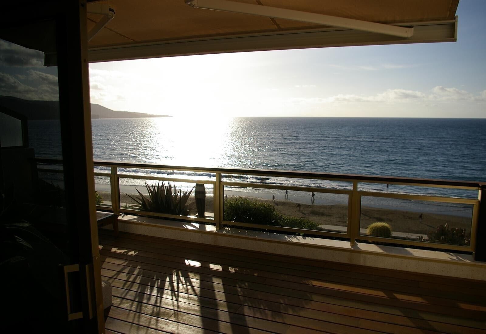 A balcony with a view of the ocean and a sunset.