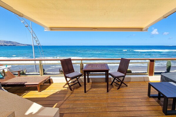 Une terrasse avec une table et des chaises, donnant sur la mer.