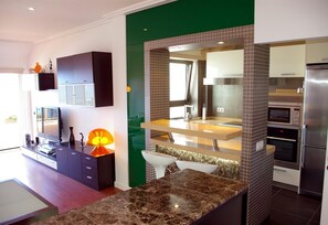 Une cuisine moderne dotée d’un plan de travail en marbre, d’appareils électroménagers intégrés et d’un mur d’accent de couleur verte.
