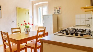 Une cuisine équipée d’une cuisinière à gaz, de chaises en bois, d’une table et d’un réfrigérateur.