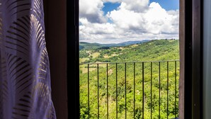 Un balcon donnant sur un paysage verdoyant et un ciel partiellement nuageux.