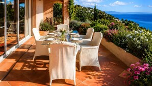 A dining area with a table set for two, overlooking a scenic view of the sea. - Villa Bellevue with Panoramic Views · South-Facing · Overlooking Saint-Tropez (Roquebrune-sur-Argens)