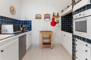 Une cuisine compacte équipée d’un four à micro-ondes, d’une machine à café et d’une étagère en bois.