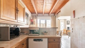 Una cocina compacta con gabinetes de madera, microondas, cafetera y lavavajillas.
