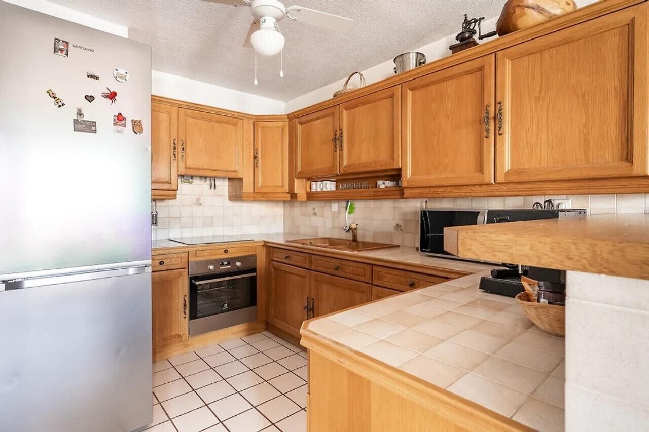 Una cucina con mobili in legno, un frigorifero, un forno a microonde e un lavello.
