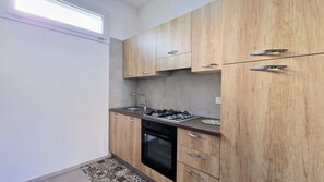 Une cuisine de taille réduite, dotée de meubles en bois, d’une cuisinière à gaz, d’un évier et d’un four.