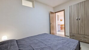 Une chambre à coucher comprenant un lit, une armoire et une porte donnant sur un coin repas.