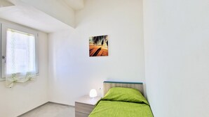 A bedroom with a bed, a nightstand, a wall-mounted picture, and a window with curtains. - Apartment 'Appartamento Della Luna 2' with Sea View, Balcony and Wi-Fi (Alcamo)