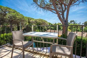 A balcony with a table and two chairs, overlooking a lush green landscape and a large tree. - Villa Regina with Private Pool – Les Issambres / Côte d’Azur (Roquebrune-sur-Argens)