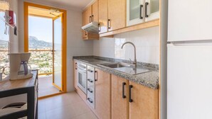 A compact kitchen with granite countertops, a built-in oven, and a sink. - Apartamento Ambar Beach by Costa CarpeDiem (Calpe)