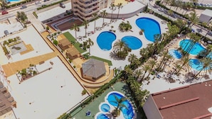 An aerial view of a hotel with multiple swimming pools, palm trees, and a covered area with a roof. - Apartamento Ambar Beach by Costa CarpeDiem (Calpe)