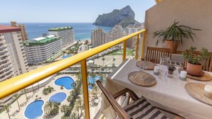 A balcony with a view of a coastal cityscape, including a mountain and a pool area. - Apartamento Ambar Beach by Costa CarpeDiem (Calpe)