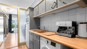 A modern kitchen with a washing machine, coffee maker, and a wooden countertop. - Apartment 200 m from Calanques & Sea, Wi-Fi, Air Conditioning, Private Parking (Saint-Aygulf)
