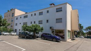 A multi-story building with a parking lot, several parked cars, and a tree in front. - Apartment 200 m from Calanques & Sea, Wi-Fi, Air Conditioning, Private Parking (Saint-Aygulf)