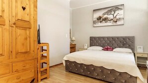 A bedroom with a bed, a wooden wardrobe, a ladder, a nightstand, a lamp, and a wall-mounted picture. - Apartment 200 m from Calanques & Sea, Wi-Fi, Air Conditioning, Private Parking (Saint-Aygulf)