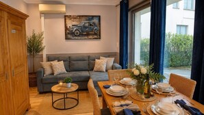 A furnished living room with a sofa, a dining table set for four, and a painting on the wall. - Apartment 200 m from Calanques & Sea, Wi-Fi, Air Conditioning, Private Parking (Saint-Aygulf)