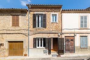 Un edificio de piedra con puerta de madera, un balcón y una ventana pequeña.