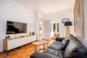 Ein modernes Wohnzimmer mit Flachbildfernseher, einer Holzkonsole, einer Couch, einem runden Couchtisch und einem Gemälde an der Wand.
