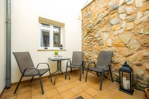 A small outdoor seating area with two chairs, a table, and a potted plant.