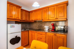 Eine Küche mit Holzausstattung, einem Kühlschrank, einer Mikrowelle, einem Wasserkocher und einem Toaster.