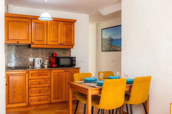 A compact kitchen with wooden cabinets, a microwave, a kettle, and a coffee maker.