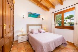 A bedroom with a bed, nightstands, a painting, and a window with curtains. - Holiday Home 'Finca Kelly' with Pool, Wi-Fi and Air Conditioning (Artá)