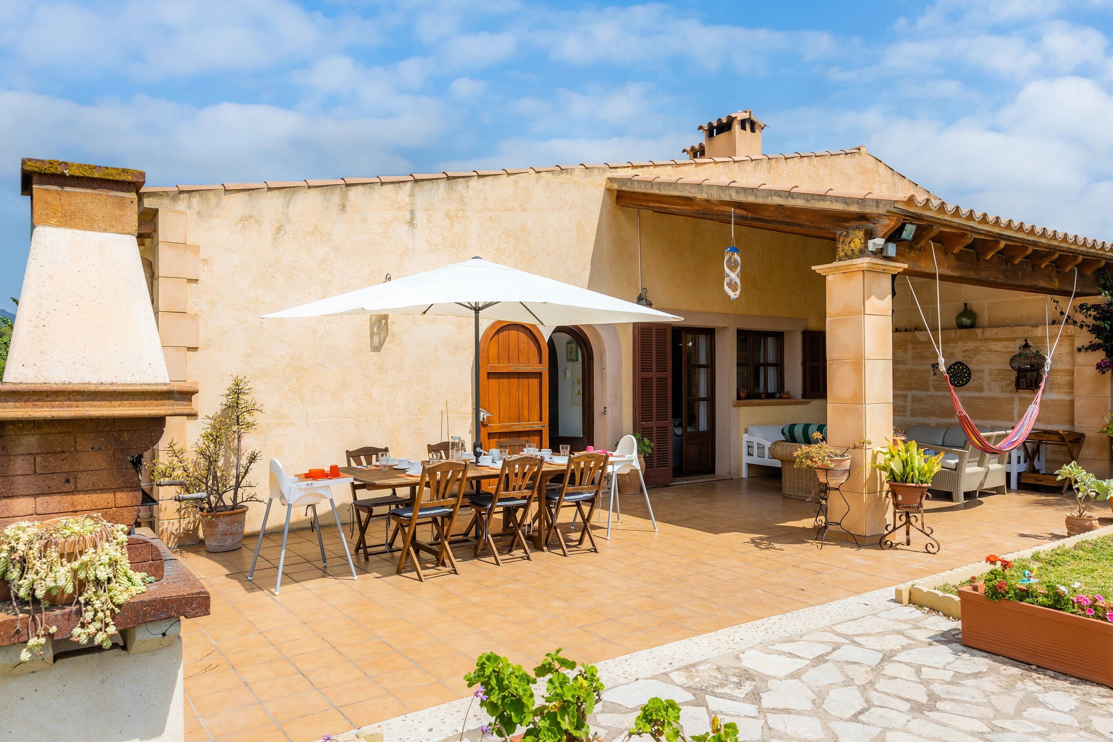 Une terrasse extérieure avec une table à manger, des chaises et un parasol blanc.