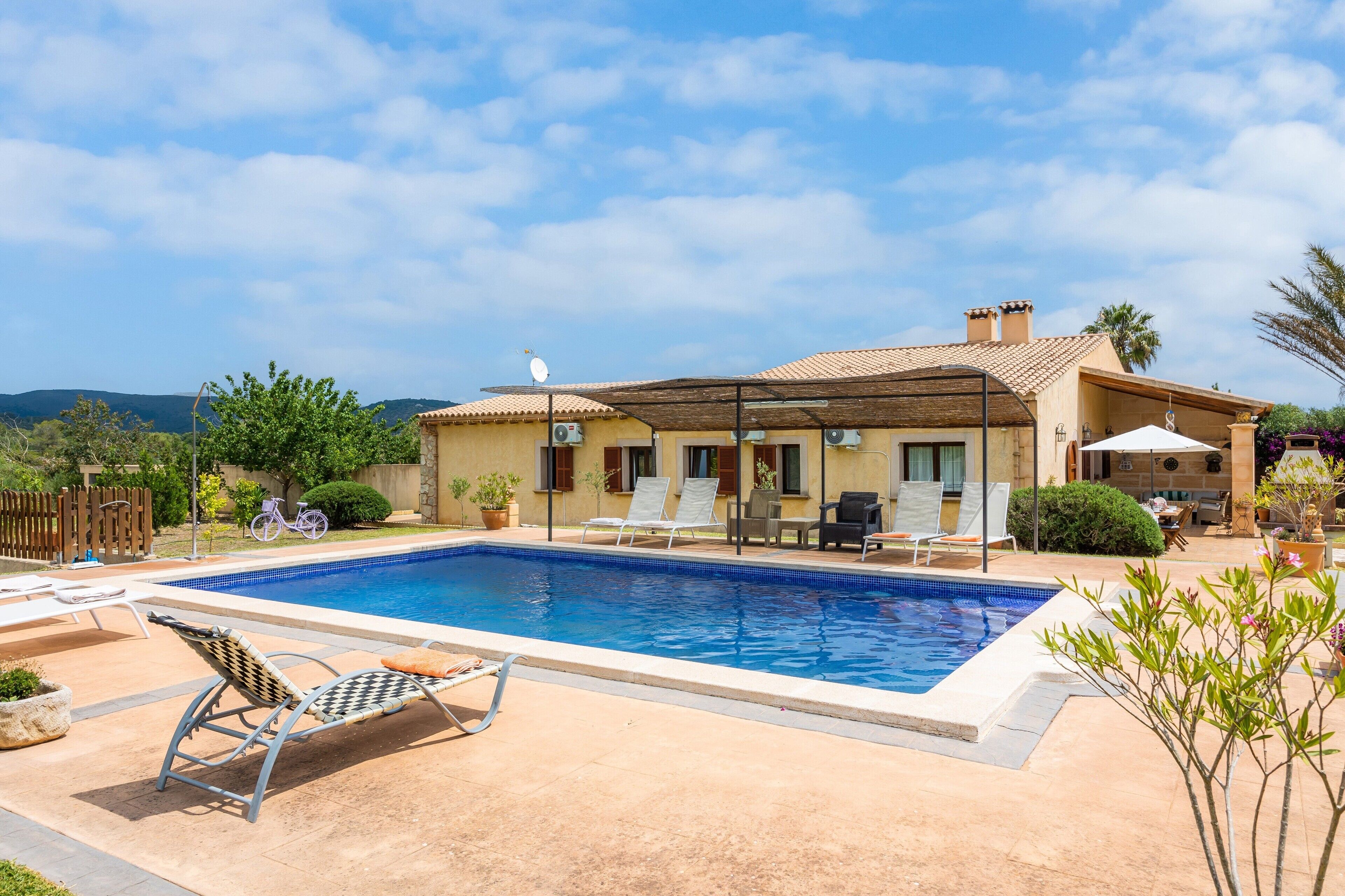 Une maison avec une piscine, du mobilier d’extérieur et un vélo.