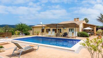 Une maison avec une piscine, du mobilier d’extérieur et un vélo.