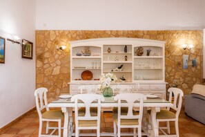 A dining area with a stone wall, white furniture, and decorative items.