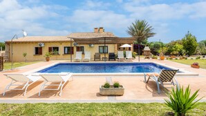 Una casa con piscina, mobiliario de exterior y jardín.