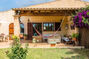 A house with a patio, outdoor furniture, and a hammock. - Holiday Home 'Finca Kelly' with Pool, Wi-Fi and Air Conditioning (Artá)