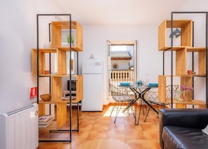A compact living space with a kitchen, dining area, and a black leather sofa.