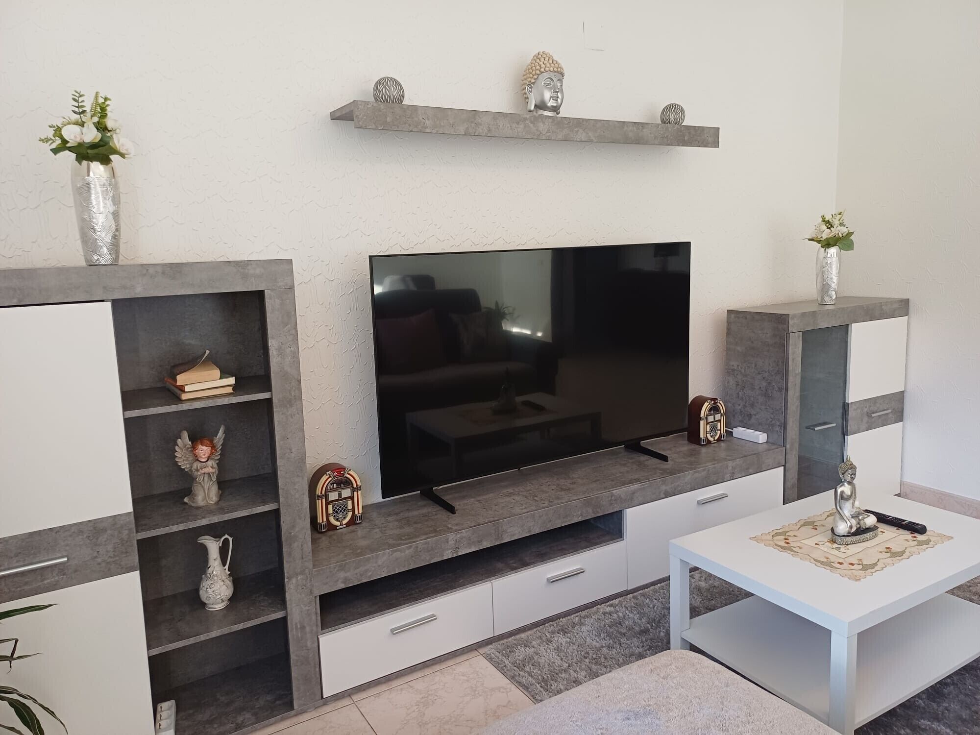 Un saló modern amb televisió plana, prestatges integrats i objectes decoratius.