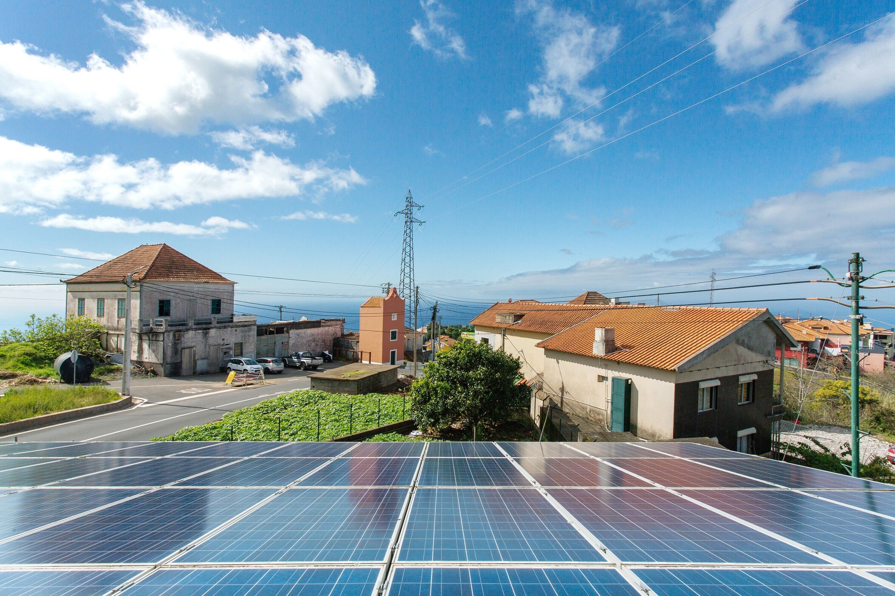 A residential area with solar panels, a road, and houses with red-tiled roofs.