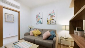 Ein Wohnzimmer mit einer Couch, einem Couchtisch, einer Lampe und zwei an der Wand hängenden Bildern.