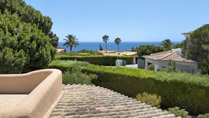 Una propiedad costera con una escalera de piedra, abundante vegetación y vista al mar.