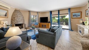 Una sala de estar con chimenea de piedra, un sofá, un televisor y un ventanal grande.