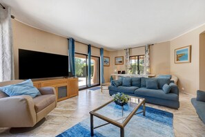 A living room with a sofa, a coffee table, a TV, and a large window.