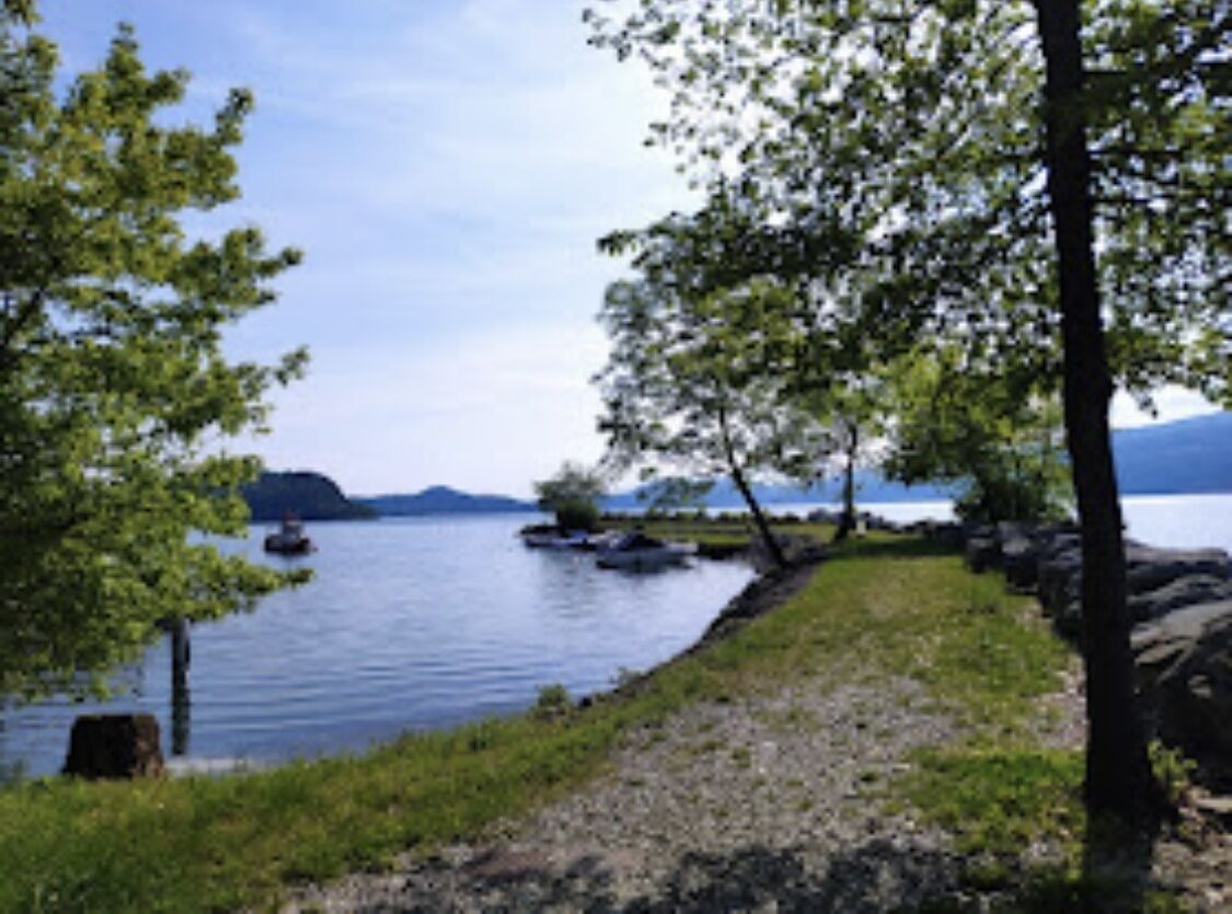 Vista su un lago con alberi, una zona erbosa e una sponda rocciosa.