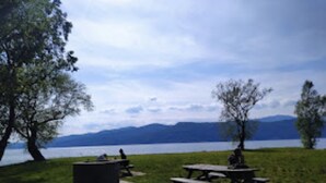 Un espace de pique-nique au bord du lac, équipé de bancs et d’un foyer.