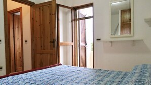 Un dormitorio con cama, armario de madera y ventana con persianas.
