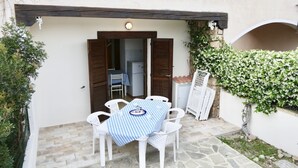 Un patio al aire libre con mesa y sillas, una pequeña cocina y un camino de piedra.