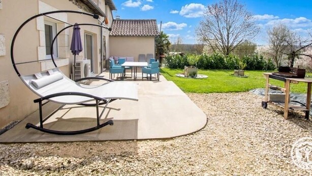 A patio with a lounge chair, a table, and chairs.