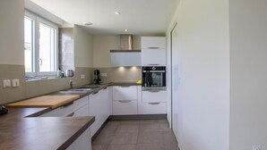 A modern kitchen with white cabinets, a wooden countertop, a built-in oven, and a window providing natural light.